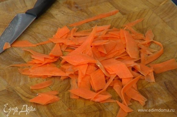 Морковь почистить и нарезать тонкими длинными полосками (можно воспользоваться овощечисткой), затем порезать полоски небольшими кусочками наискосок.
