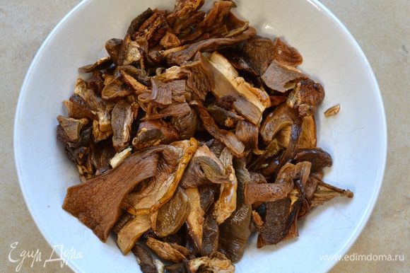 Замоченные грибы слейте и как следует отожмите. Добавьте их в сотейник к овощам. Помешивая, дайте грибам хорошо обжариться, до появления интенсивного запаха.