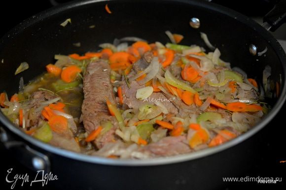 Затем добавим на эту же сковороду/жаровню порезанный сельдерей, морковь, лук готовить до мягкости овощей. Добавить чеснок 2 дольки мелко порубленный и тушить, помешивая, 2 минуты. Влить бульон, сухие грибы с жидкостью, вино. Вернуть мясо, перемешать. Тушить примерно 1 час. Разогреть духовку до 180°C.