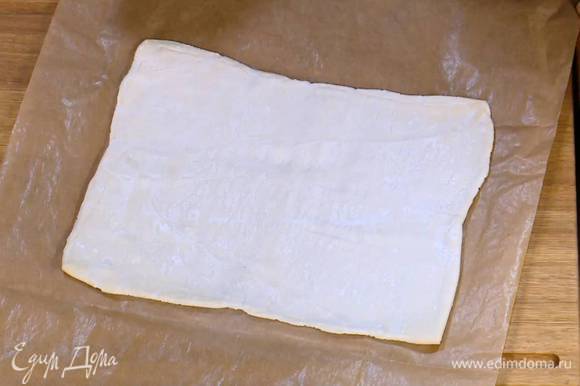 Тесто предварительно разморозить, затем выложить на лист бумаги для выпечки, раскатать не слишком тонко и разрезать на 4 квадрата.
