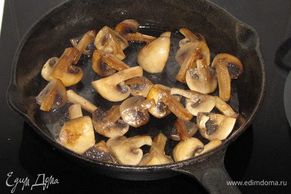 Пока мясо запекается, приготовим грибы. Разрезать крупные шампиньоны на 4 части, мелкие пополам или оставить целиком. Разогреть в сковороде растительное масло и обжарить шампиньоны до готовности, постоянно помешивая, чтобы получить золотистый цвет.