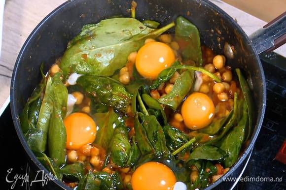 Яйца разбить на шпинат с нутом, накрыть сковороду крышкой и обжаривать все до готовности яиц.
