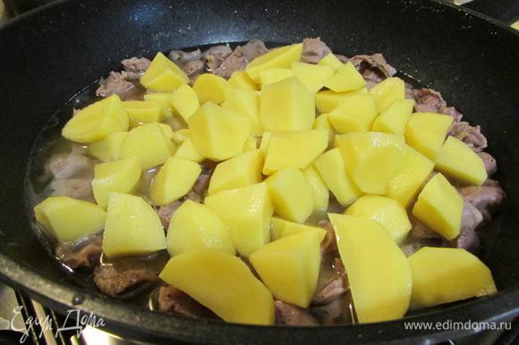 Через 1,5 часа к желудкам добавить картофель. Закрыть сковороду крышкой и тушить до готовности картофеля.