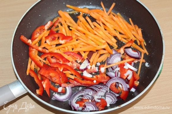 Затем слегка обжарить порезанные соломкой: морковь, перец и лук. Всыпать туда острый перец. Прогреть перец и перемешать с овощами.