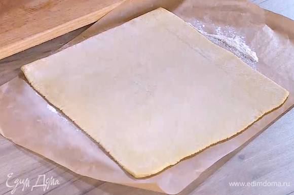 Рабочую поверхность посыпать мукой и раскатать предварительно размороженное тесто в тонкий пласт.