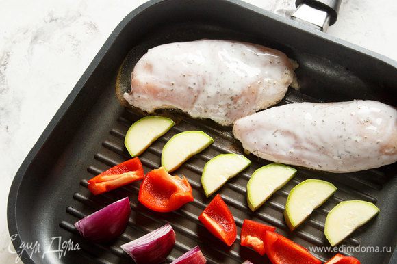 Красный лук, кабачки и болгарский перец нарезать. Достать из холодильника курицу. Выложить курицу и подготовленные овощи на гриль, обжарить до готовности.