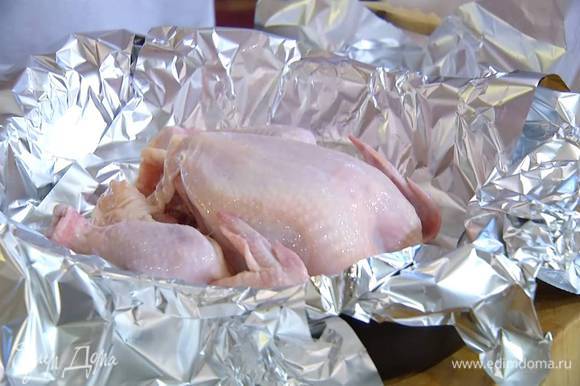 Тушку цыпленка вымыть, обсушить, посолить и поперчить изнутри, затем выложить грудкой вверх на противень, выстеленный фольгой так, чтобы свешивались края.