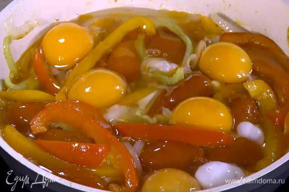 Добавить в сковороду помидоры, посолить, разбить сверху яйца и готовить под крышкой.