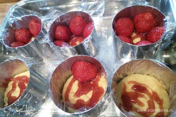 Смазать донышко пирожного клубничным вареньем и выложить половинки клубничек разрезом наружу, широкой стороной вниз. Мелкие целые ягоды кладем в середину.