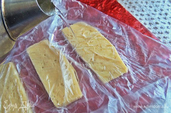 Прямо на ломтики плеснуть горячей воды из чайника. Это нужно для того, чтобы сыр стал эластичным и свернулся в рулет.