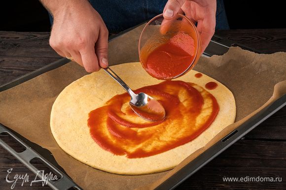 Тонко раскатать тесто и положить его в форму. Смазать всю поверхность теста томатным соусом.