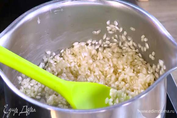 В кастрюле среднего размера растопить сливочное масло, затем всыпать рис и слегка прогреть, чтобы он пропитался маслом и стал прозрачным.