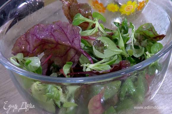 В глубокую посуду влить заправку, выложить салатные листья и все перемешать.