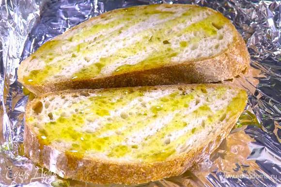 Хлеб выложить на противень, выстеленный пищевой фольгой, сбрызнуть оливковым маслом и поджаривать пару минут под разогретым грилем.