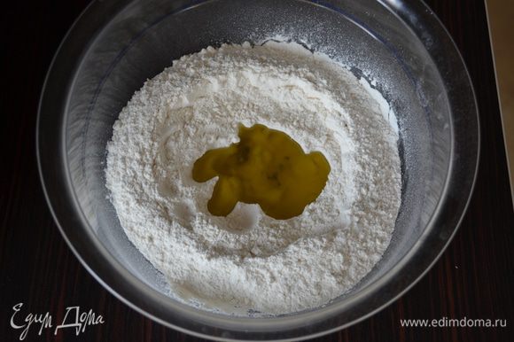 Просеять в миску 200 г муки, добавить соль. Сделать в муке углубление и добавить оливковое масло.