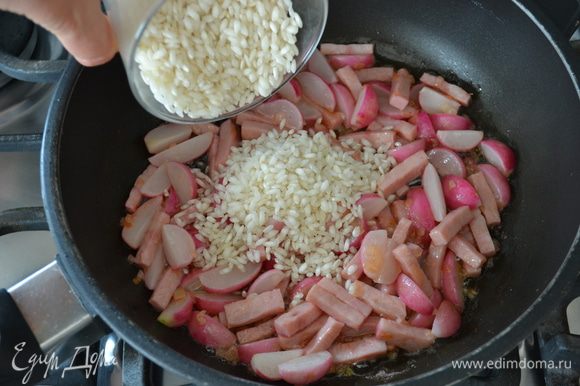 Следом всыпать рис (предварительно не промывать!) и перемешать, чтобы он смешался со всеми ароматами в сковороде.