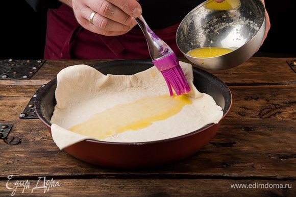 Первый слой смазать растопленным маслом, выложить на него второй слой и промазать маслом. В небольшую круглую форму уложить тесто так, чтобы свисали края.