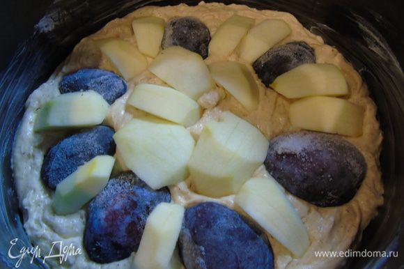 Форму 24 см смажьте маслом и выложите тесто. Сверху выкладываем сливы (у меня замороженная) и яблоки, которые предварительно очистите и нарежьте средними кусочками.