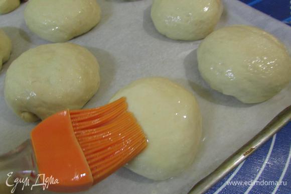 Противень застелить бумагой для выпечки, обязательно смазать сливочным маслом. Выложить подготовленные булочки швом вниз. И смазать их яйцом.