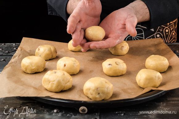Выложить тесто на присыпанную мукой доску, руками распределить в пласт, затем сложить его пополам и еще раз пополам. Сформировать булочки.