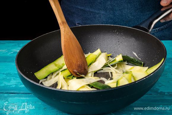 Цукини режем тонкими пластинами, лук — тонкой соломкой и обжариваем на оливковом масле на отдельной сковороде.