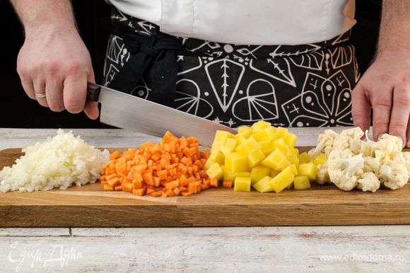 Овощи помыть и почистить. Лук, картофель и морковь нарезать кубиками. Цветную капусту разобрать на соцветия.