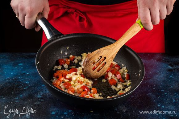 Обжарьте на сковороде в растительном масле чеснок в течение 1 минуты, добавьте лук и перец, пассеруйте 10 минут, постоянно помешивая овощи.