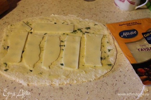 Тесто разделить на две части, каждую раскатать в прямоугольник толщиной 3–5 мм. Обильно смазать начинкой из масла. Сверху выложить сыр.