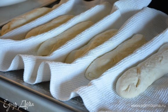 Полотенце присыпать мукой, выложить хлеб на полотенце швом вверх, сделать бортики между хлебушками.