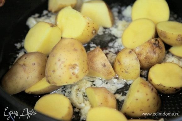 Разогреть духовку до 180°С. Нагреть масло в жаропрочной посуде и обжарить чеснок и картошку 10 минут.