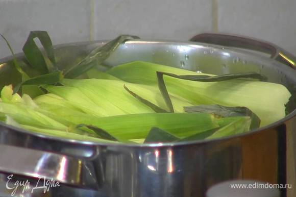 В большой кастрюле вскипятить воду, поместить в нее кукурузу, так чтобы она была покрыта водой, сверху разложить кукурузные листья, накрыть крышкой и варить 20 минут.