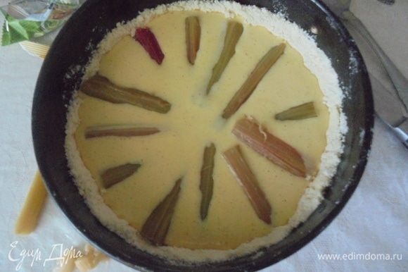 Тесто выложите в смазанную маслом круглую форму для выпекания, оформите бортики, залейте на основу ванильный крем. Сверху разложите кусочки ревеня.