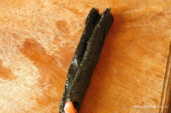Завершаем обертку, срезаем лишний лист нори, получается кусочек семги с двумя зубчиками в нори — это хвост рыбы.
