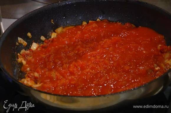 Выложить к луку с чесноком томатную пасту, перемешать, затем добавить помидоры в собственном соку и все прогреть.