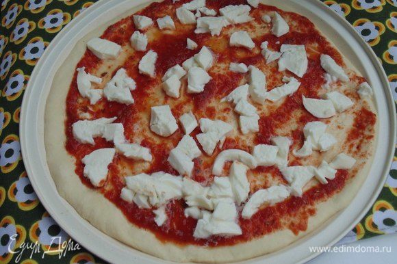 Моцареллу порезать небольшими кусочками. Смазать соусом пиццу, выложить моцареллу. Выпекать 10 минут.