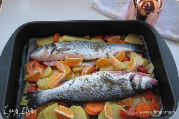 Форму для запекания смазать оливковым маслом, выложить овощи, сверху рыбу. Рыбу сбрызнуть оставшимся оливковым маслом, влить сухое белое вино. Запекать при температуре 180°С около 30 минут до готовности блюда.