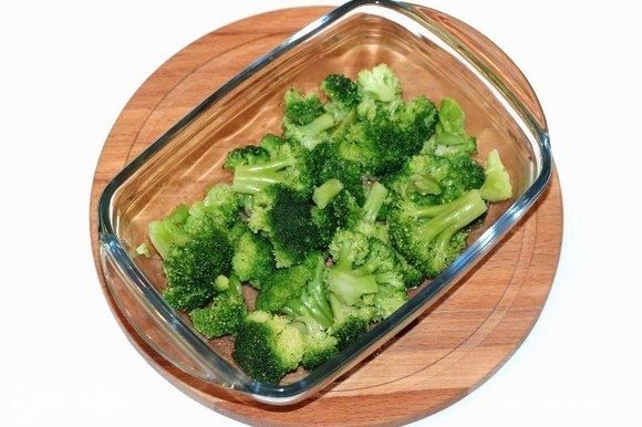 Капусту брокколи выложить в кипящую воду, 1-2 минуты бланшировать и выложить в сито. Форму для запекания смазать растительным маслом и выложить капусту.