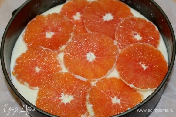 Выложить тесто в форму на 20 см, апельсины очистить, порезать тонкими кружочками, выложить сверху на тесто.