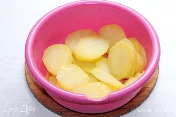 Очищенный картофель нарезаем тонкими кружочками (~0,5 см) и отвариваем в подсоленной воде до полуготовности. Затем отвар сливаем, картофель выкладываем в миску.