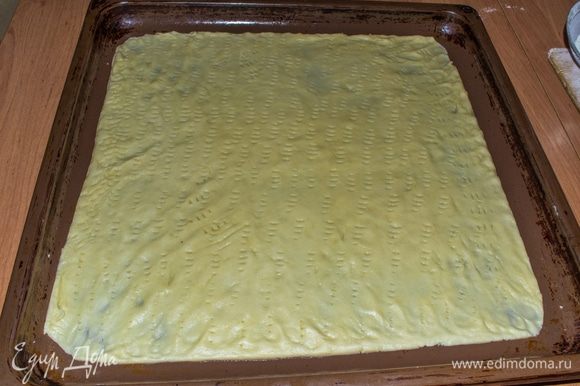 От замешанного теста нужно отделить небольшой кусок (размером с кулак) и поместить его в морозилку до полного замерзания ~15 минут. Оставшееся тесто раскатать на слегка смазанным маслом противне в толщину ~2-3 мм. Наколоть вилкой.