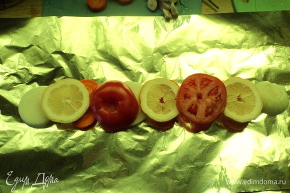 На фольгу разложили нарезанные помидоры, лимон, лук-репку.