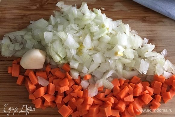 Подготовим овощи для мясного хлеба. Почистим 1 среднего размера луковицу, морковь и зубчик чеснока. Мелким кубиком нарезать лук и морковь. Зубчик чеснока раздавить тыльной стороной ножа и измельчить.