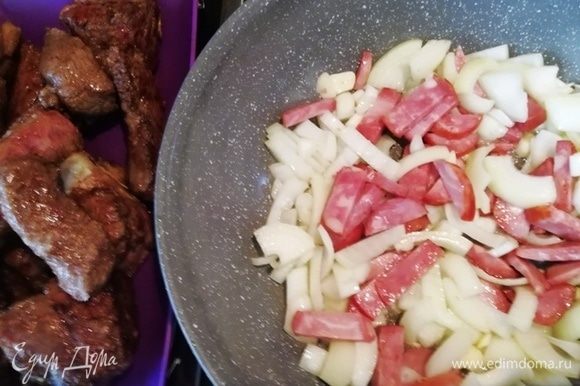 Выкладываем из сковороды говядину и на вытопившемся жире обжариваем лук и колбасу.
