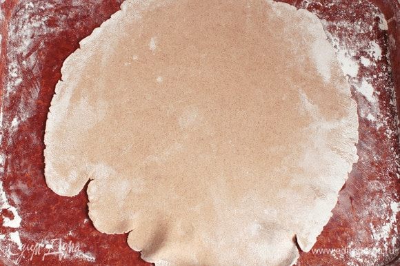 Аккуратно вытянуть «отдохнувшее» тесто в очень тонкий пласт на припыленной пшеничной мукой поверхности. Если не получается, то воспользуйтесь скалкой.