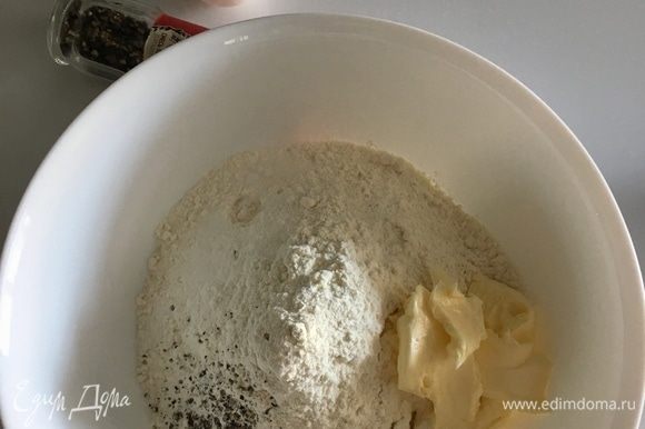 В большую чашу просеять муку с солью и свежемолотым перцем. Добавить мягкое сливочное масло и влить дрожжевое молоко. Начать вымешивать тесто.
