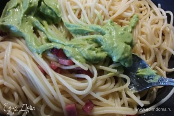 Готовые спагетти выложить в сковороду с колбасками (небольшое количество воды, в которой они варились, отобрать). Соус из авокадо выложить в спагетти, добавь воду для более сочной консистенции, размешать.
