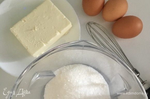 В другую емкость отмерить сахар. Подготовить три яйца и сливочное масло. Масло должно быть непременно мягкое, растаявшее при комнатной температуре.