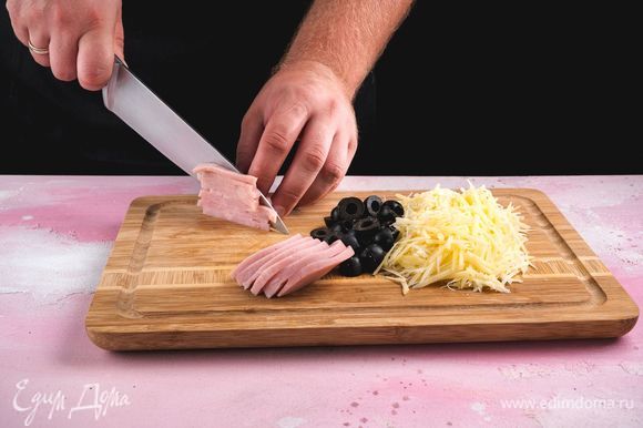 Сыр натрите на терке, ветчину нарежьте соломкой, маслины — пополам.