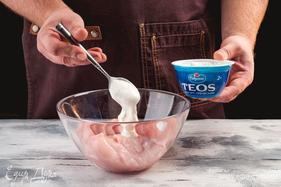 Выложите куриные грудки в миску, добавьте греческий йогурт «TEOS».