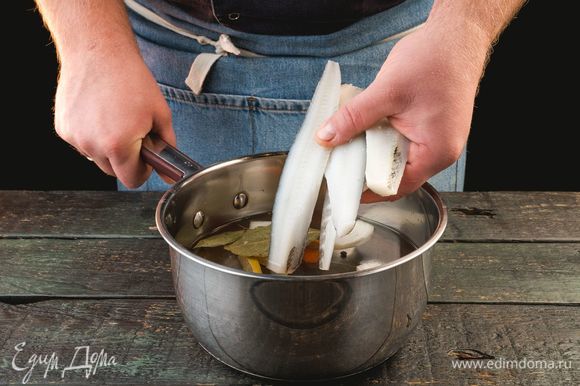 Положите рыбу в кастрюлю, залейте водой, добавьте лавровый лист, лук, морковь, перец горошком и пару долек лимона. Поставьте на огонь и варите в течение 15 минут. Процедите бульон.
